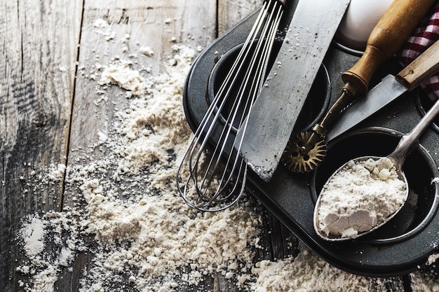 Conceito de cozimento cozinha utensílios de cozinha acessórios para assar no fundo de madeira com farinha. vista do topo. processo de cozimento. ninguém.