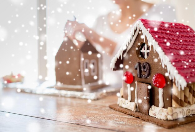 conceito de cozinha, pessoas, natal e decoração - mulher feliz fazendo casas de gengibre em casa