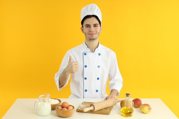 Conceito de cozinhar jovem chef masculino em fundo amarelo