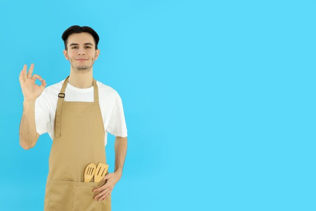 Foto conceito de cozinhar jovem de avental em fundo azul