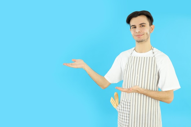 Conceito de cozinhar jovem de avental em fundo azul