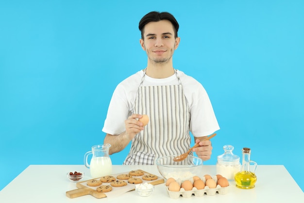 Conceito de cozinhar jovem de avental em fundo azul