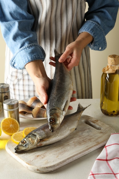 Conceito de cozinhar peixe com mulher segura arenque fresco