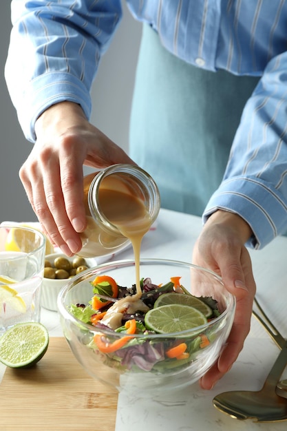 Conceito de cozinhar salada de legumes com molho de tahine na mesa de madeira branca