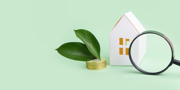 Foto conceito de crédito fiscal verde pequena casa com moedas perto dela folhas verdes e lupa