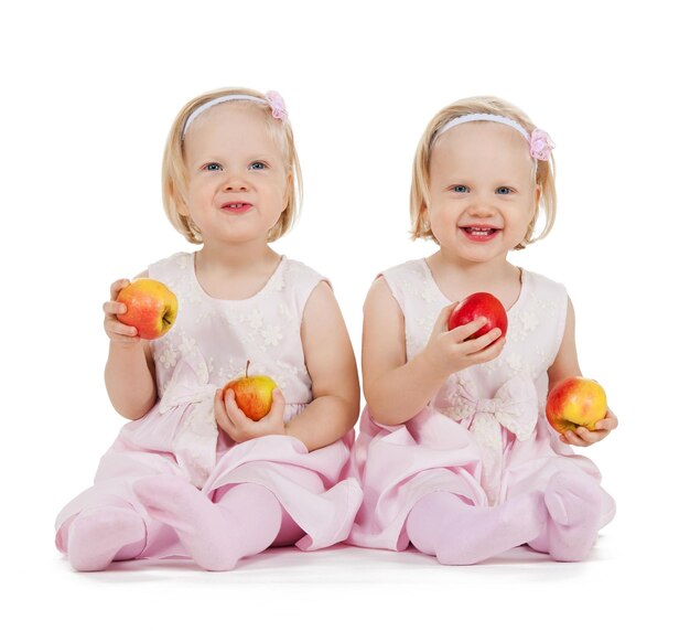 conceito de crianças, comida e gêmeos - duas gêmeas idênticas brincando com maçãs