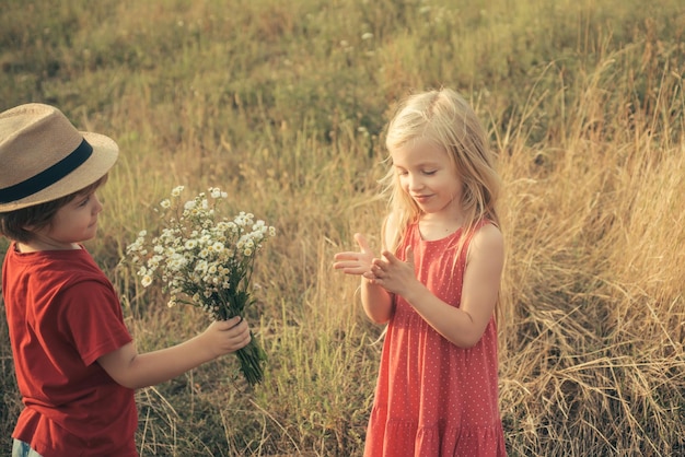 Conceito de crianças de aventura e férias Crianças felizes menina e menino abraçam no prado no verão na natureza Anjinhos apaixonados Feliz dia dos namorados Conceito de amor de puericultura Primeiro amor