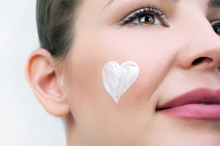Foto conceito de cuidado de pele facial. uma jovem tem um coração de creme no rosto.