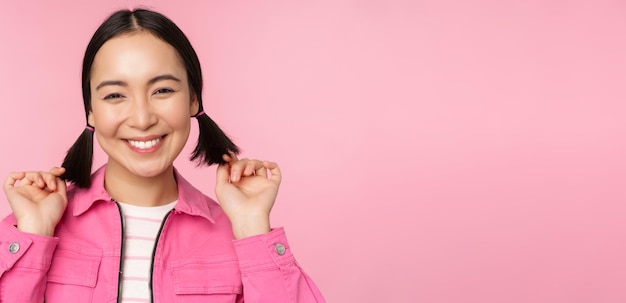 Conceito de cuidados com a pele e cosmetologia Linda garota asiática sorrindo e rindo mostrando uma pele facial limpa e saudável posando contra um fundo rosa Copiar espaço