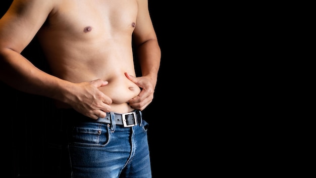 Conceito de cuidados com o corpo Homem sem camisa e mão beliscando-o excesso de gordura da barriga Homens insalubres gordos corpo celulite isolado em fundo preto