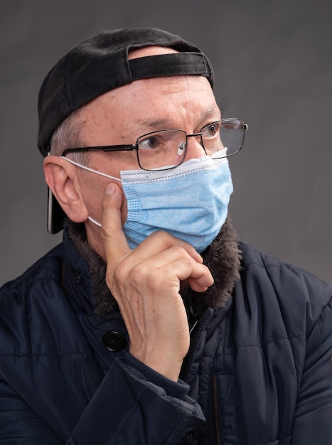 Conceito de cuidados de saúde. Último homem com máscara protetora posando em estúdio sobre fundo cinza