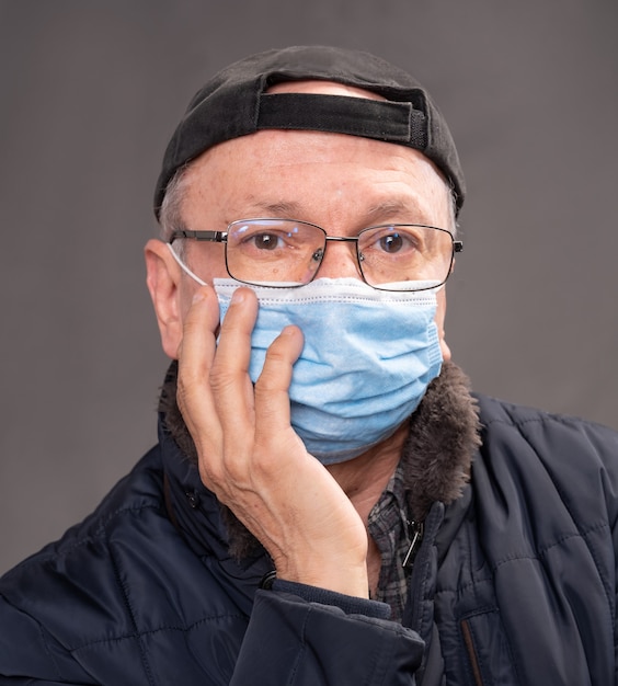Conceito de cuidados de saúde. Último homem com máscara protetora posando em estúdio sobre fundo cinza