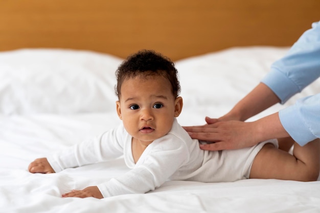 Conceito de cuidados infantis mãe fazendo massagem nas costas para menino preto fofo