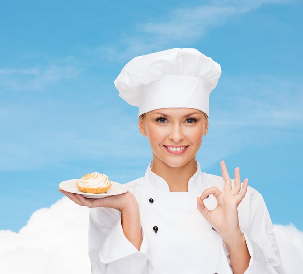 conceito de culinária e comida - chef feminino sorridente, cozinheiro ou padeiro com torta no prato e sinal de ok