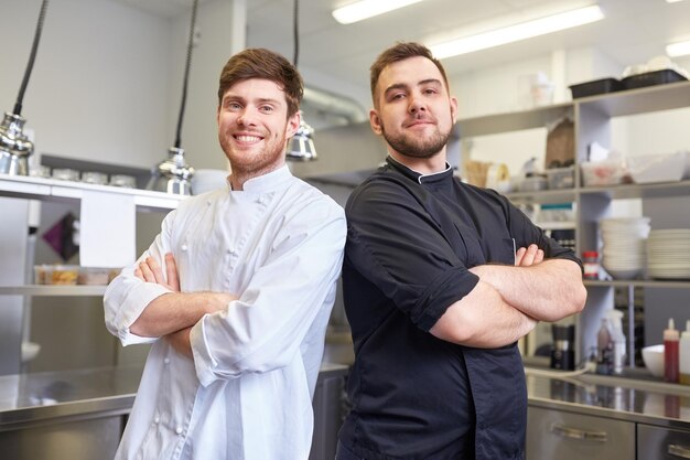 conceito de culinária, profissão e pessoas - chef e cozinheiro masculino feliz na cozinha de um restaurante