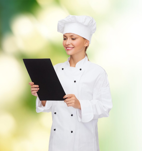 conceito de culinária, propaganda e comida - chef, cozinheiro ou padeiro feminino sorridente com papel de menu preto em branco