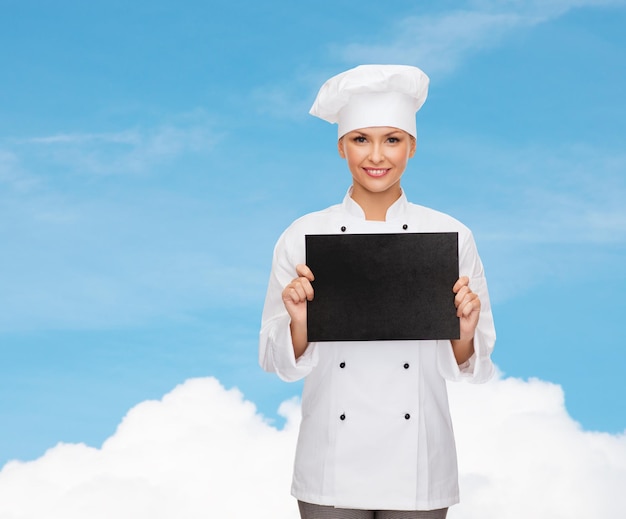 conceito de culinária, propaganda e comida - chef feminino sorridente, cozinheiro ou padeiro com papel preto em branco