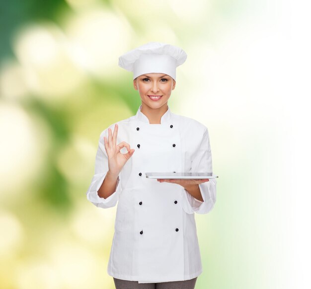 conceito de culinária, tecnologia e pessoas - chef feminino sorridente, cozinheiro ou padeiro com computador tablet pc mostrando gesto okey sobre fundo verde