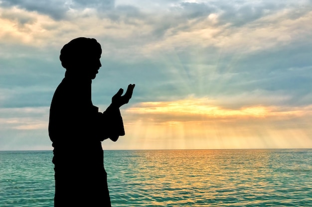 Conceito de cultura islâmica. Silhueta de homem orando no fundo do mar e um lindo pôr do sol