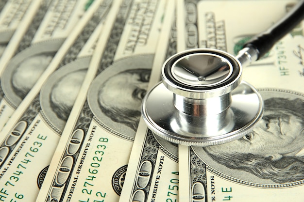 Conceito de custo de saúde: estetoscópio e dólares isolados no branco