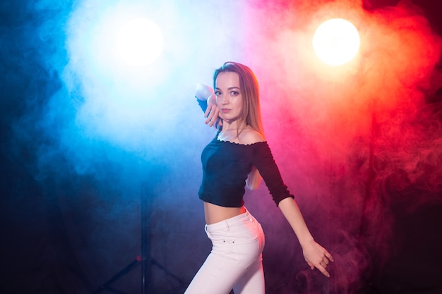 Conceito de dança, graça e elegância - jovem mulher dançando bachata no escuro, luzes e