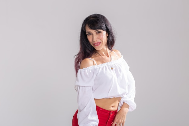 Conceito de dança latina, strip dance, contemporâneo e bachata lady - mulher dançando improvisação e movendo seus longos cabelos em uma parede branca.
