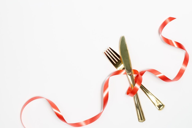 Conceito de decoração de natal Conjunto de talheres consiste em garfos e facas decorando com fita vermelha