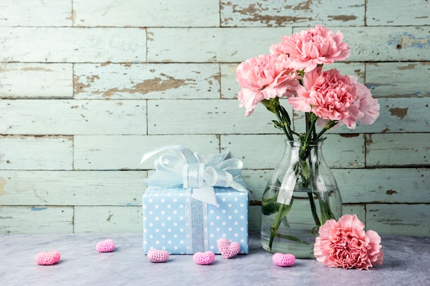 Conceito de dia das mães de flores de cravo-de-rosa em garrafa clara e caixa de presente e coração