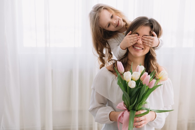 Foto conceito de dia das mães feliz. filha de criança felicita mãe e dá-lhe flores tulipas