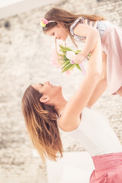 Conceito de dia das mães feliz. Mamãe leva seu filho de alegria sobre sua cabeça.