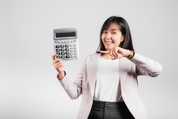 Conceito de dia de imposto. Mulher confiante sorrindo segurando calculadora e dispositivo de ponta de dedo, retrato animado feliz estúdio feminino asiático isolado em fundo branco, conta e finanças contando renda