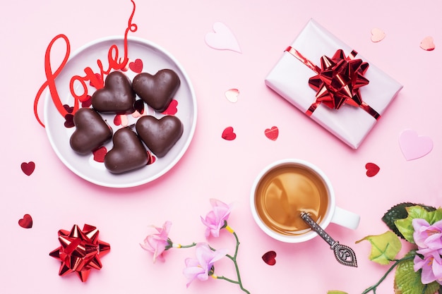 Conceito de dia dos namorados. Bombons de chocolate e café, corações em um fundo rosa. Espaço de cópia plana leigos. Cartão e presente.