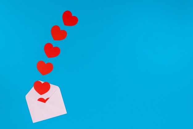 Conceito de dia dos namorados. coração vermelho sai de um envelope rosa claro