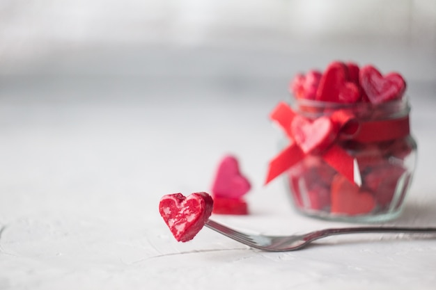 Conceito de dia dos namorados. frasco com pequenos corações vermelhos e rosa sobre um fundo claro.