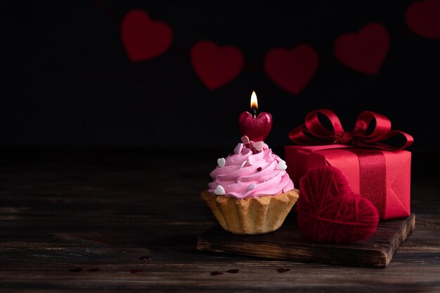 Conceito de dia dos namorados, vela em forma de coração ardente no cupcake e presente.
