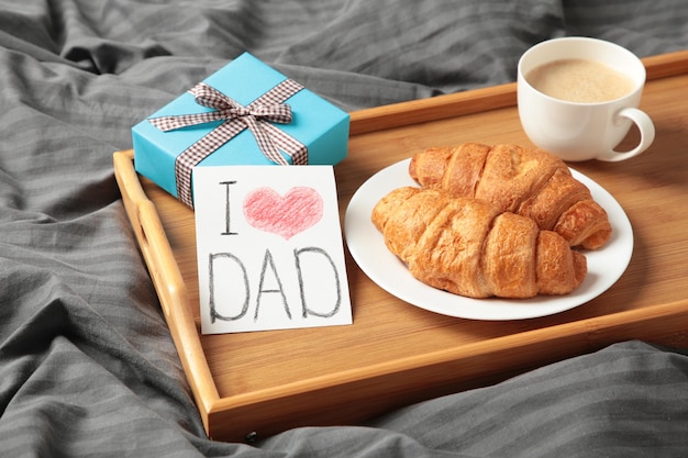 Conceito de dia dos pais com cartão-presente e café da manhã na bandeja Café da manhã para o pai com croissant e café