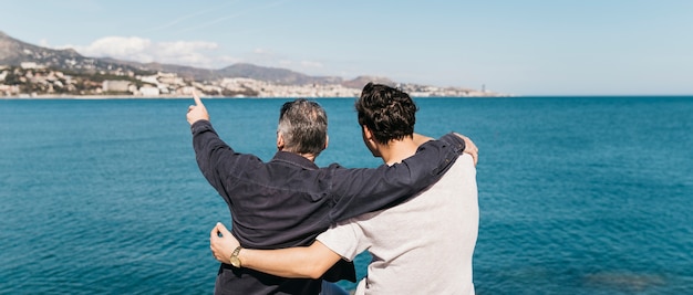 Foto conceito de dia dos pais com pai e filho olhando para o mar