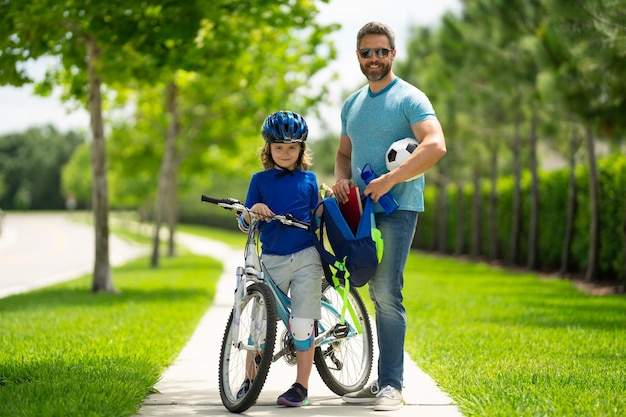 Conceito de dia dos pais pai ajudando filho a se preparar para a escola pai e filho em bicicleta num dia de verão