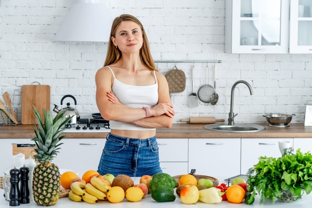 Conceito de dieta. Dieta. Mulher jovem e bonita perto na cozinha com alimentos saudáveis. Frutas e vegetais.