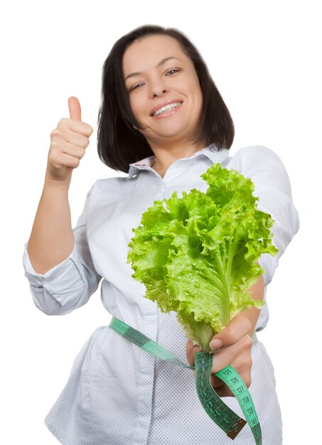 Conceito de dieta. Mulher jovem com alface medindo a cintura com fita métrica em um fundo branco