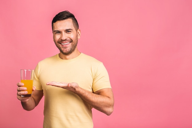 Conceito de dieta tão saborosa e saudável. Jovem atraente segurando um copo com suco de laranja detox