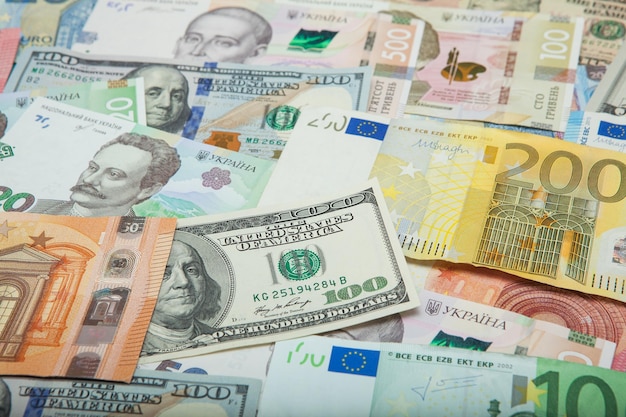 Conceito de dinheiro e finanças Nova nota de cem dólares em fundo abstrato colorido de notas de moeda nacional ucraniana americana e euro