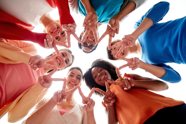 conceito de diversidade, raça, etnia e pessoas - grupo internacional de mulheres diferentes, felizes e sorridentes, deitadas no chão em círculo e mostrando sinal de mão de paz