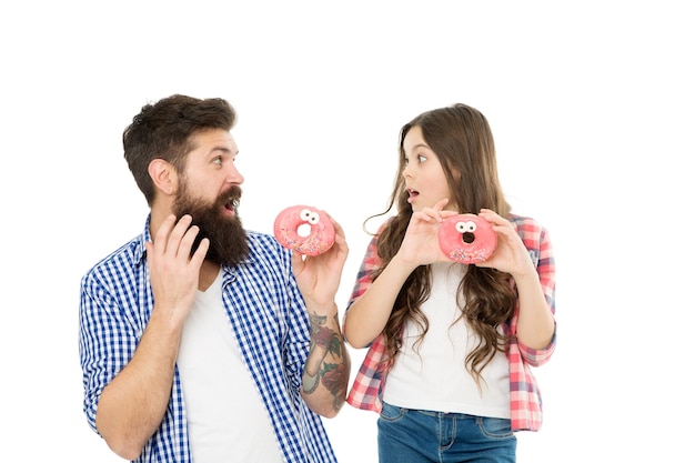 Conceito de doces e guloseimas Filha e pai comem rosquinhas doces Padaria Dia dos pais Dente doce Menina e pai seguram rosquinhas vitrificadas Família alegre Felicidade e alegria Criança faminta