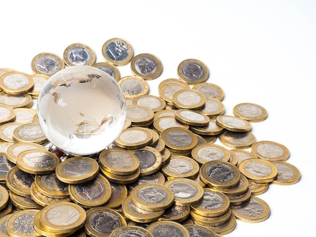 Conceito de economia global com globo de esfera e empilhado de moedas sobre branco