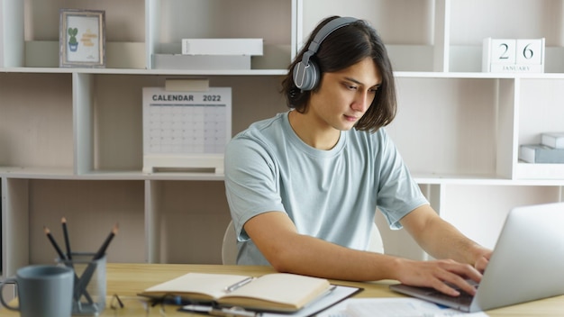 Conceito de educação a distância Garoto adolescente usa fone de ouvido para aula online e digita bate-papo no skype