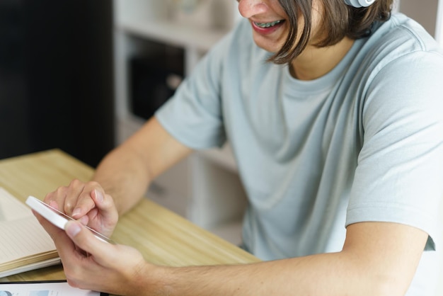 Conceito de educação a distância Menino adolescente no fone de ouvido para ouvir música e usar o telefone após o estudo on-line