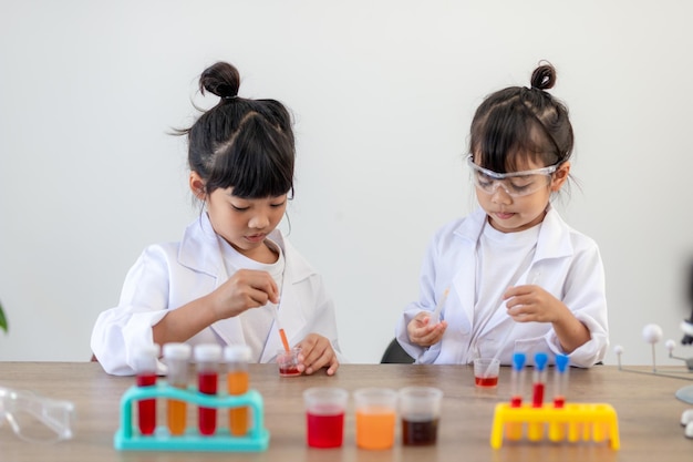 Conceito de educação, ciência, química e crianças - crianças ou estudantes com tubo de ensaio fazendo experimento no laboratório escolar