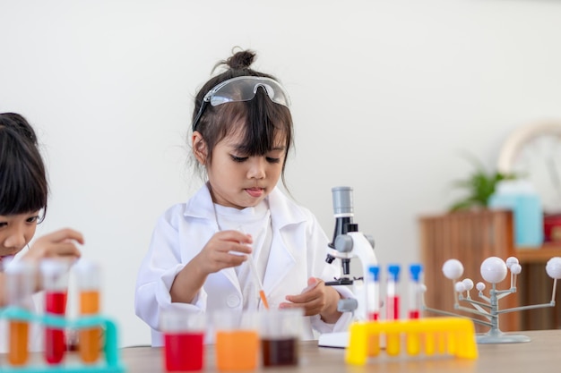 Conceito de educação, ciência, química e crianças - crianças ou estudantes com tubo de ensaio fazendo experimento no laboratório escolar