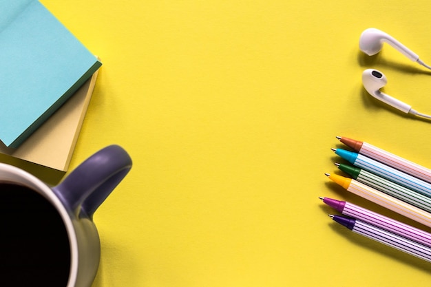 Foto conceito de educação com notas adesivas, canetas, mola e caneca de café no fundo amarelo